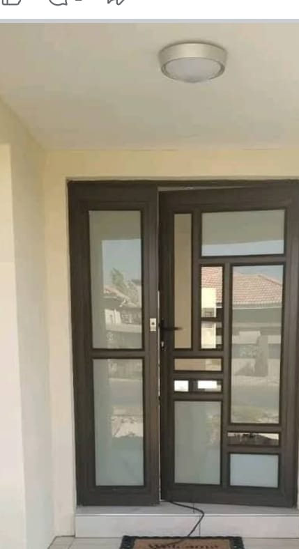Charcoal aluminium glazed double entrance door with narrow sidelights, photographed at a Botswana home — Tshipiworks