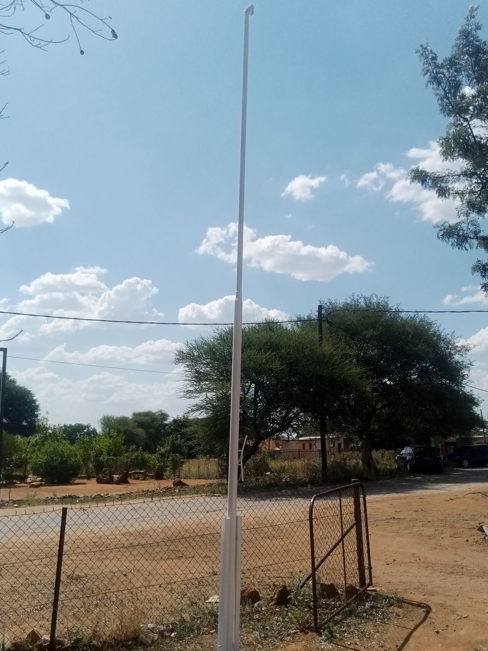 Steel flag pole fitted into a square base sleeve set in concrete, Tlokweng job — Tshipiworks