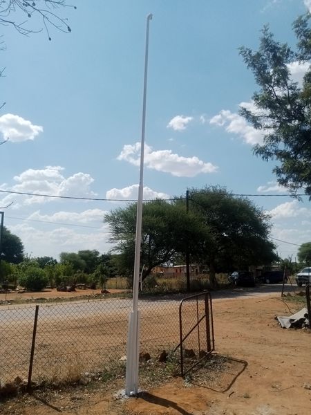 Finished white steel flag pole installed beside a boundary fence in Tlokweng, Botswana — Tshipiworks