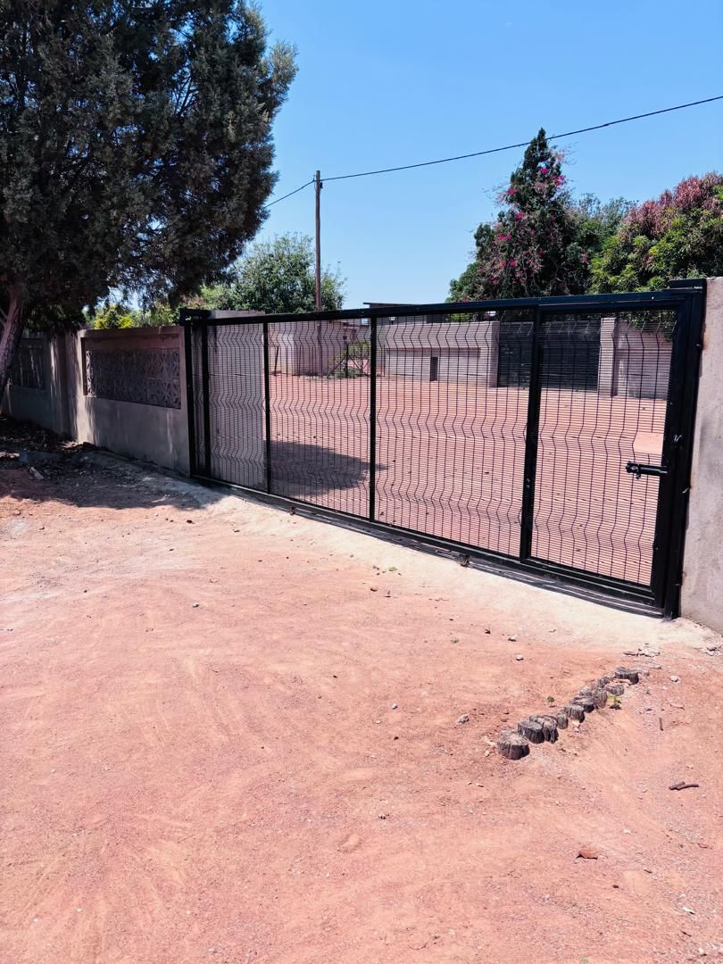 Black ClearVu sliding gate on its track with pedestrian gate section at a boundary wall in Metsimotlhabe — Tshipiworks