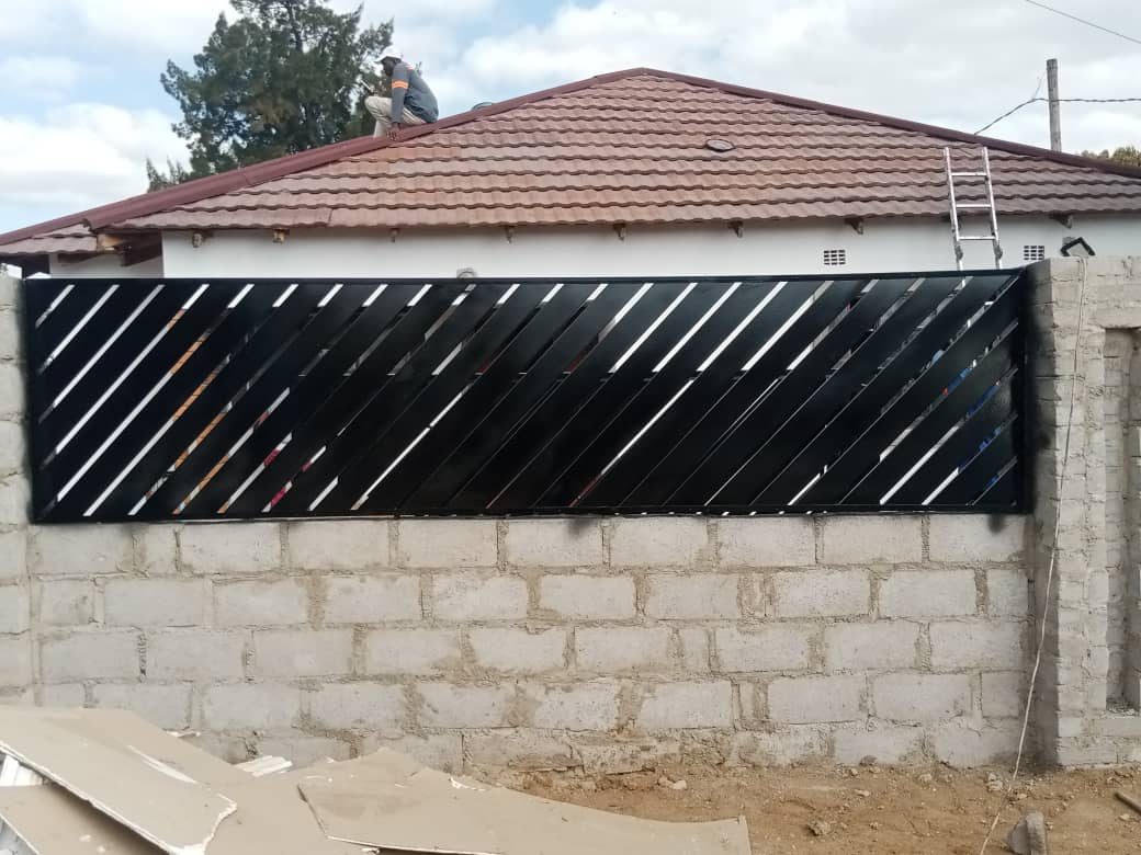 Black gate panel with angled diagonal steel slats — Tshipiworks