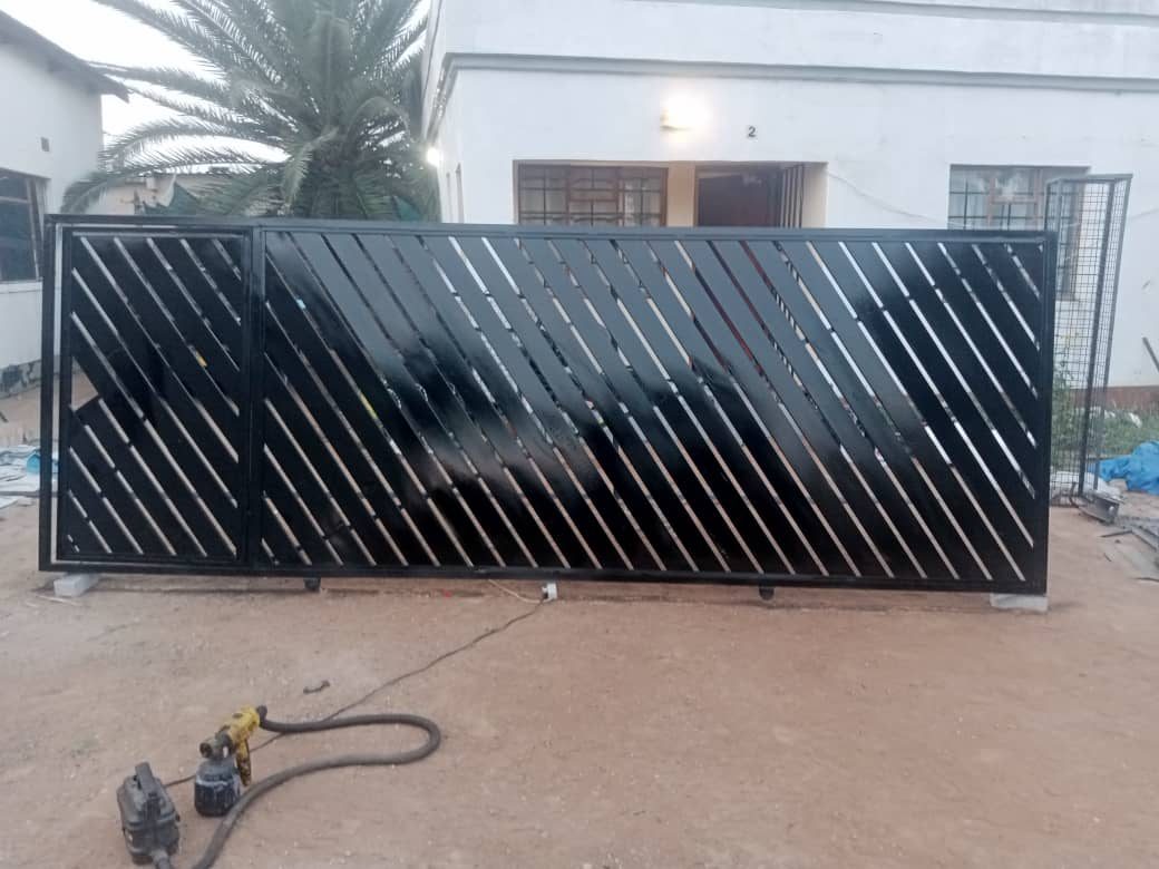 Black sliding gate with diagonal steel slats — Tshipiworks Botswana