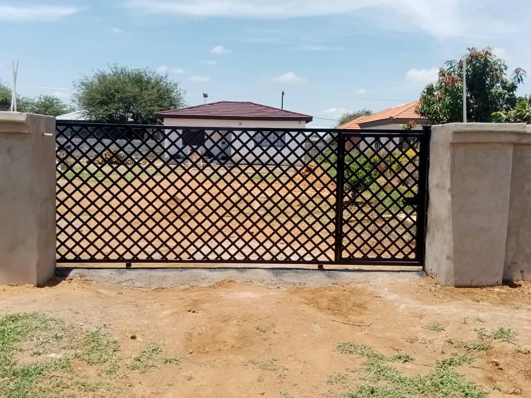 Black diamond lattice sliding gate installed between finished pillars — Tshipiworks
