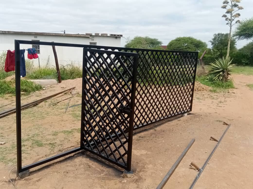 Black diamond-pattern sliding gate partially open on track — Tshipiworks