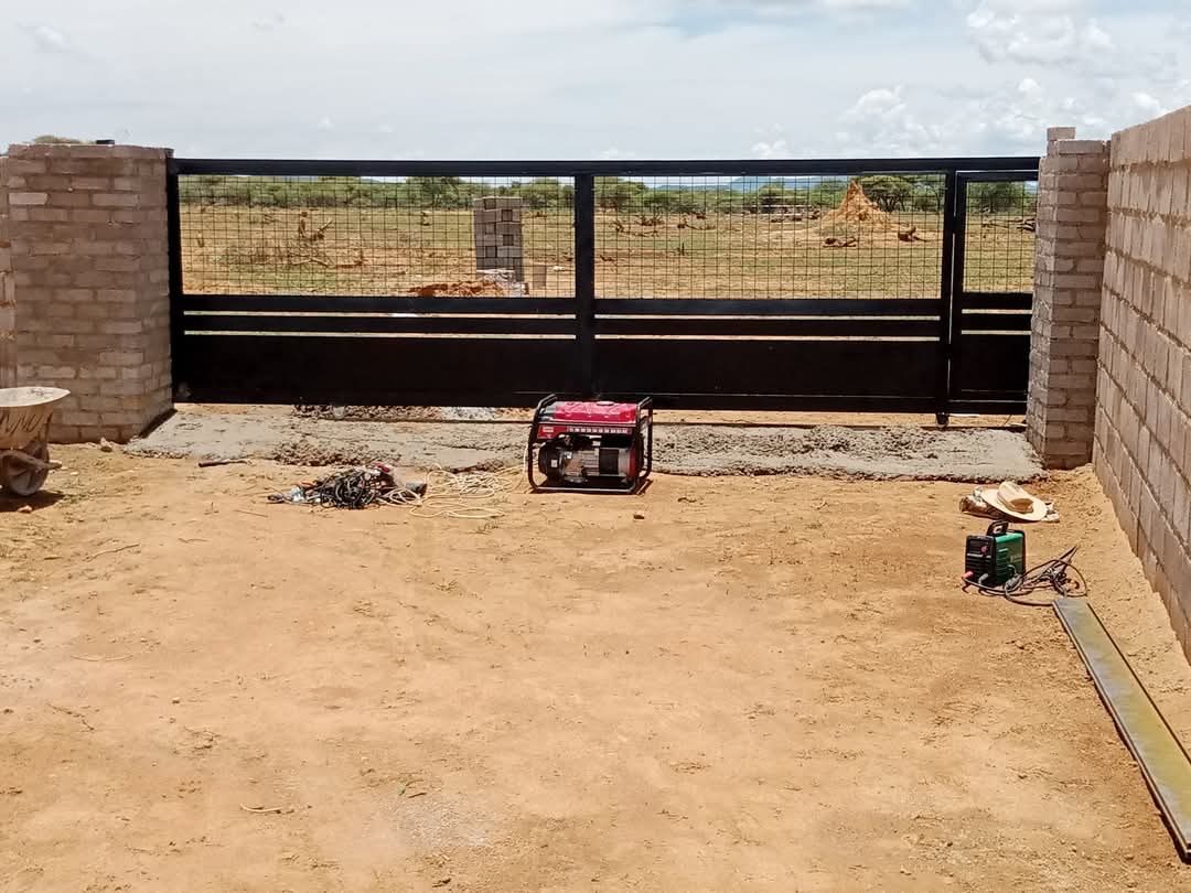 Black horizontal slat sliding gate during installation with tools on site — Tshipiworks
