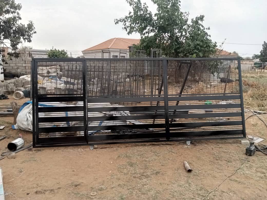 Black horizontal slat gate standing in workshop yard before install — Tshipiworks