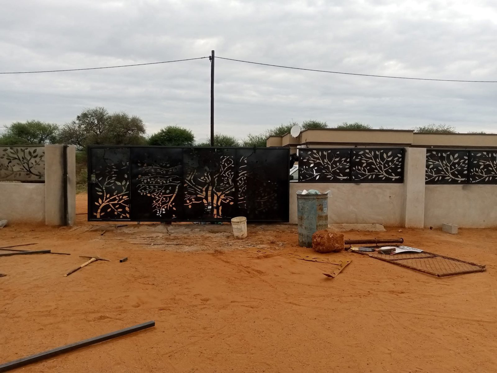 Long perimeter wall with laser-cut tree panels and matching horizontal slats — Tshipiworks