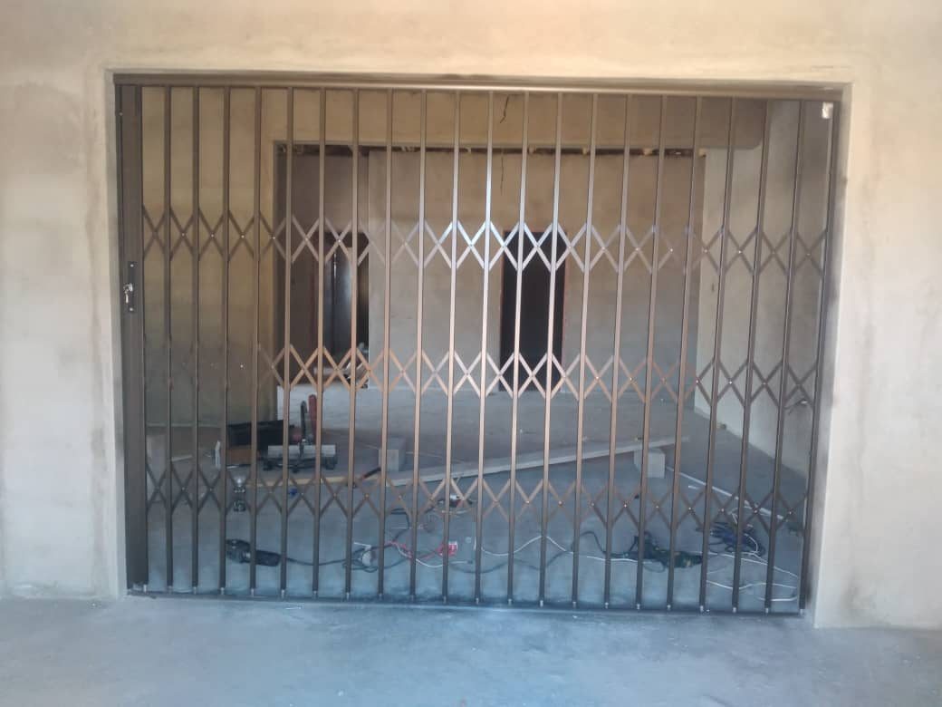 Bronze retractable steel trellidor on wide patio sliding door during install — Tshipiworks Gabane