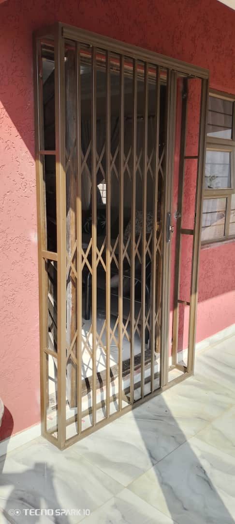 Bronze steel trellidor on exterior doorway with terracotta wall — Tshipiworks