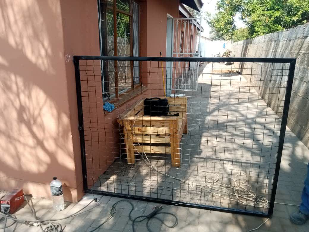 Black welded steel mesh gate panel on a paved yard — Tshipiworks